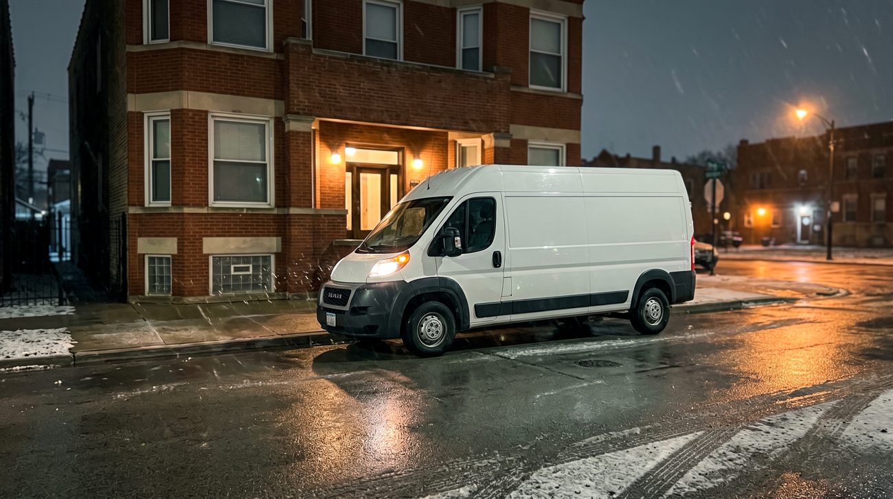 A service van parked at a Chicago curb on a wet street at night